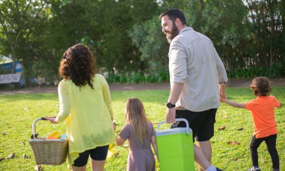 A family of four enjoys a picnic in a sunny park, capturing a joyful day outdoors.